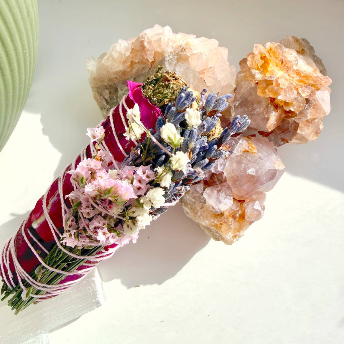 Bouquet of flowers wrapped in red ribbon with decorative stones on a white surface