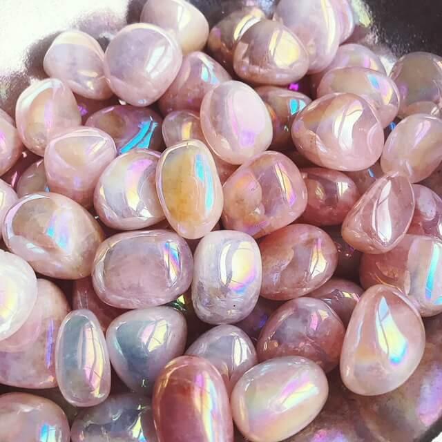 Small-sized, smooth, pink with iridescence, Angel Aura Rose Quartz tumbled pocket stones in a pile.