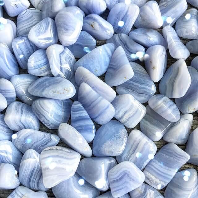 Small-sized, smooth, blue and white striped, Blue Lace Agate tumbled pocket stones in a pile.